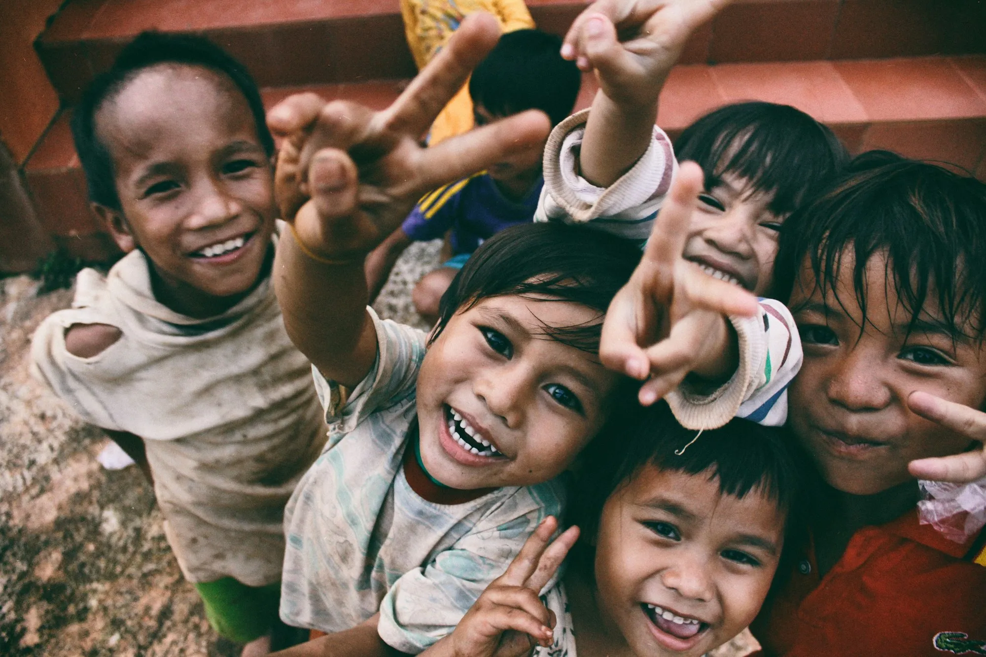 Crianças sorrindo e fazendo sinal de paz para a câmera