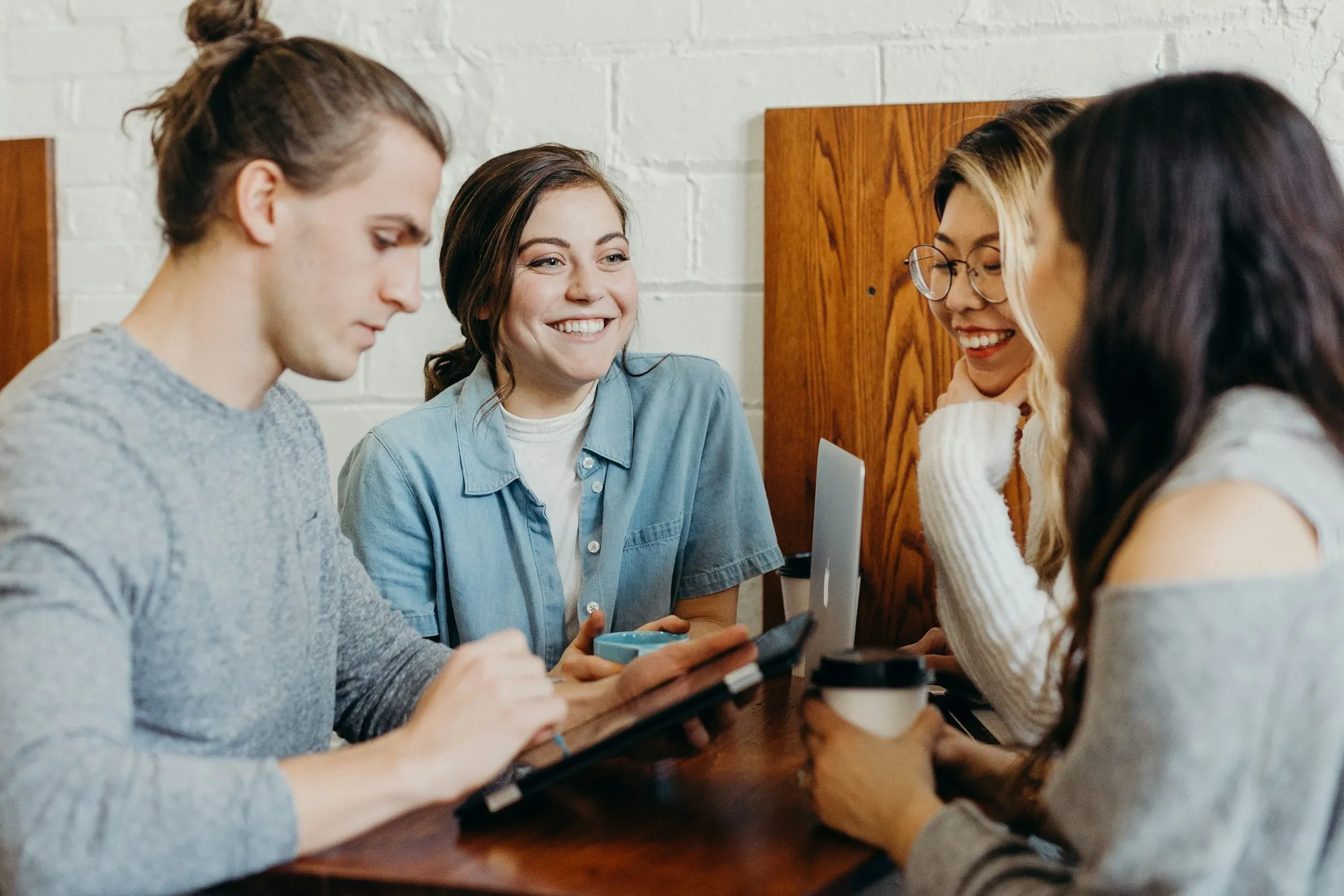 Jovens conversando e sorrindo em torno de uma mesa de madeira