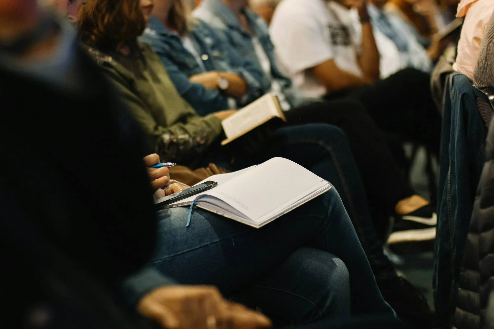 Pessoas sentadas durante uma reunião, com um caderno sobre o colo